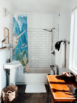 Baby Narwhal Ocean shower curtain hanging on the rod over a white bathtub