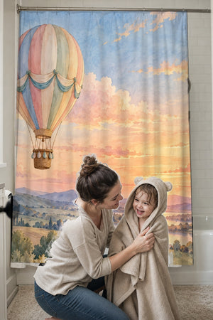 Mom drying her toddler in a hooded towel in front of the Sunset Flight Hot Air Balloon shower curtain