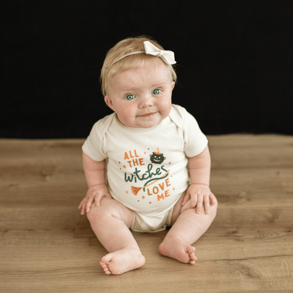 Short sleeve graphic bodysuit for babies with "Witches Love Me" design. Perfect for Halloween or everyday wear.