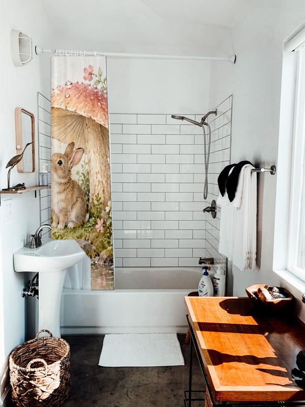 After the Rain Bunny shower curtain hanging on the rod over a white bathtub