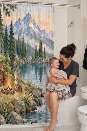 Mom holding her baby on the tub edge next to the Woodland Adventure Camping shower curtain