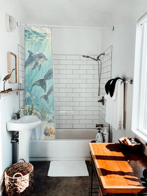 Dolphin Family Ocean shower curtain hanging on the rod over a white bathtub