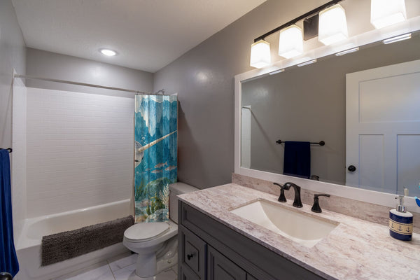 Baby Narwhal Ocean shower curtain pulled open in a gray kids bathroom