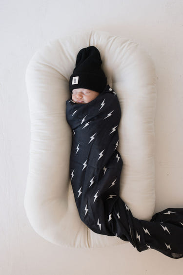Muslin swaddle featuring a midnight lightning bolt design, perfect for wrapping your baby in comfort and style.