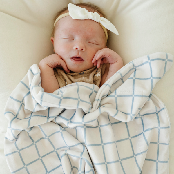 Minky stretch receiving blankets in soft colors, angled view showcasing cozy texture and versatility for babies.