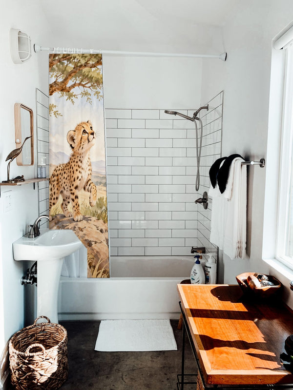 Cheetah Cub Safari shower curtain hanging on the rod over a white bathtub