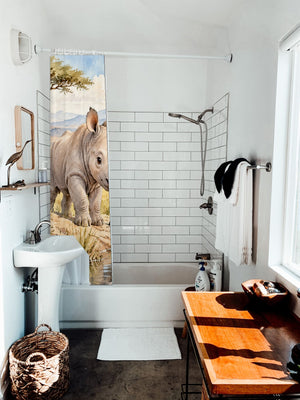 Baby Rhino Safari shower curtain hanging on the rod over a white bathtub