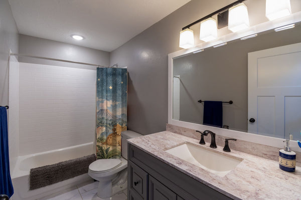Moonlit Dinosaurs shower curtain pulled open in a gray kids bathroom