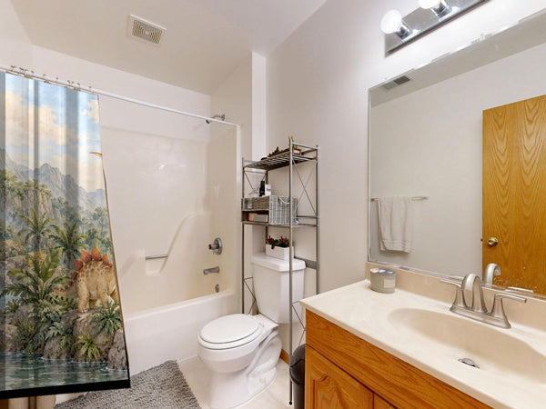 Tropical Dinosaur Garden shower curtain on a tub shower combo in an American family bathroom