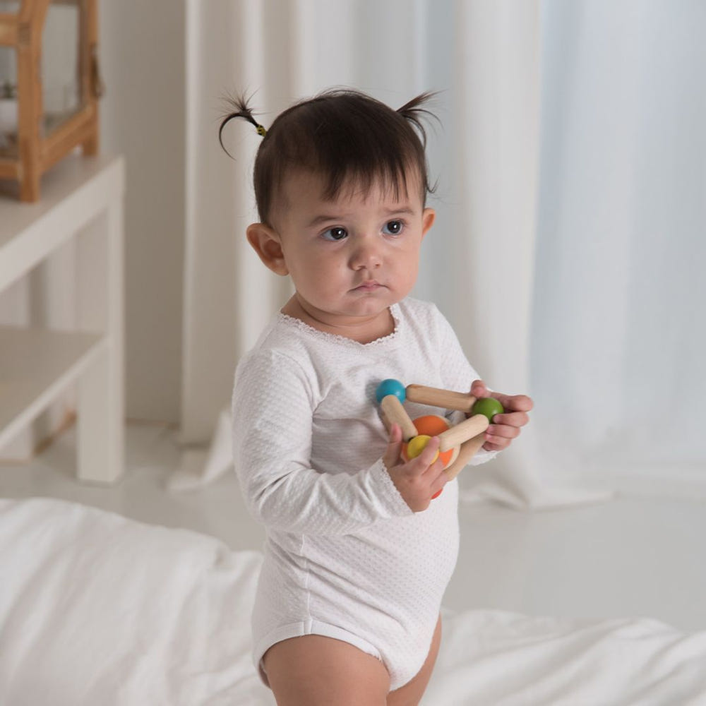Colorful triangle clutching toy for babies, promoting sensory play and motor skills development.