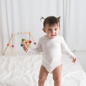 Colorful triangle clutching toy for babies, promoting sensory play and motor skills development. Angle view.