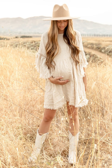 Beige raw edge bell sleeve babydoll maternity dress for stylish and comfortable pregnancy wear.