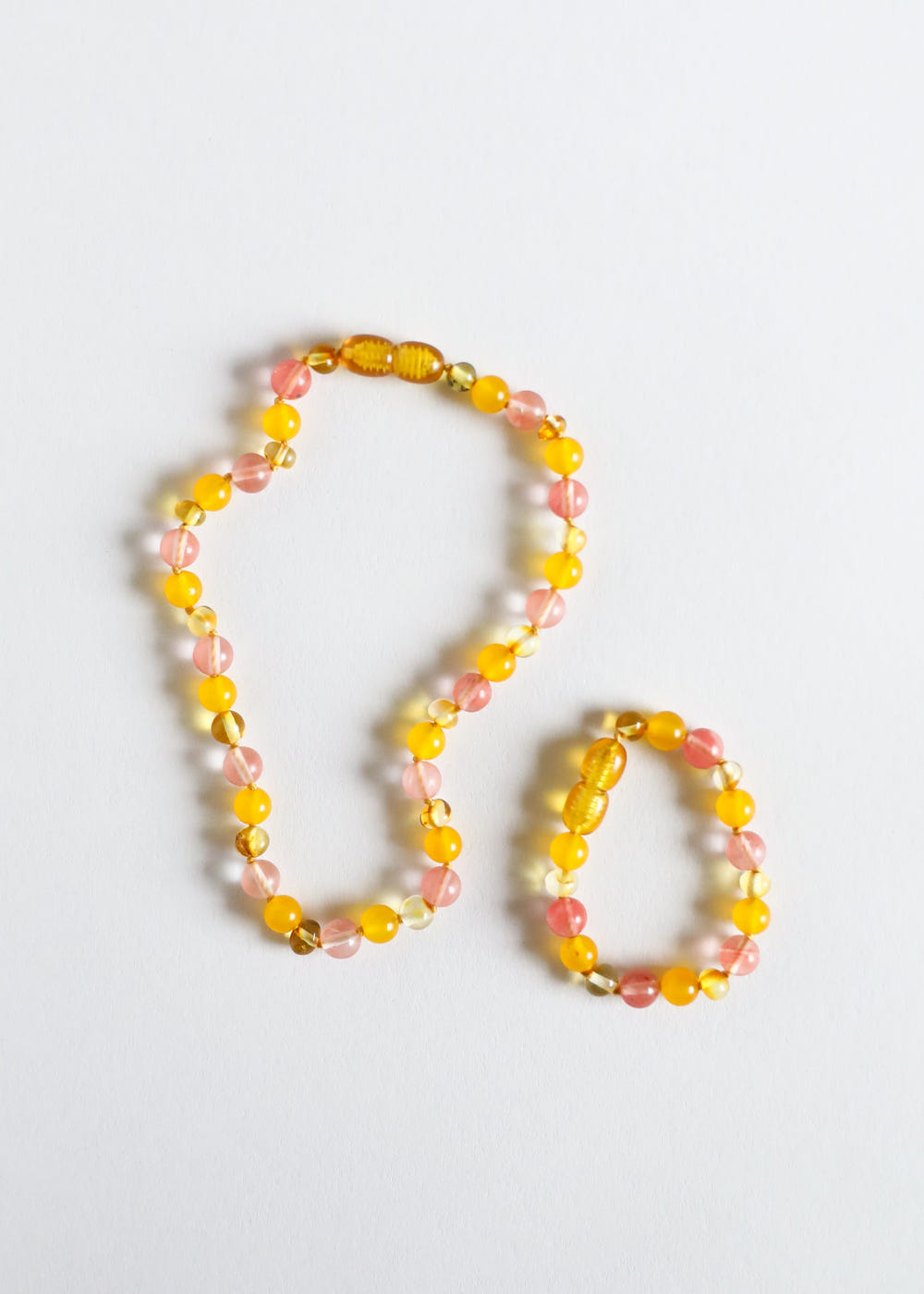 Polished honey Baltic amber and honeysuckle gemstone necklace for kids, perfect for teething and stylish wear.
