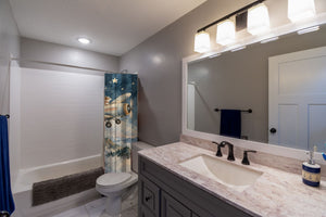 Moonlit Flight shower curtain pulled open in a gray kids bathroom