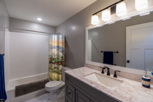Sunrise Train shower curtain pulled open in a gray kids bathroom