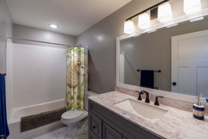 Lamb Meadow Farm shower curtain pulled open in a gray kids bathroom