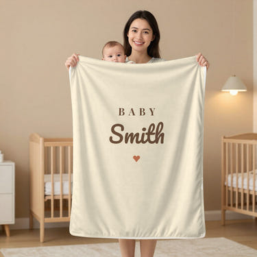 Baby Surname swaddle blanket in oat, held by a mom