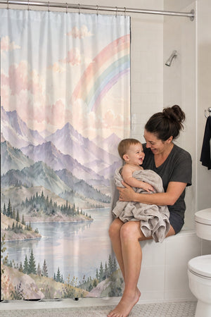 Mom holding her baby on the tub edge next to the Lavender Peaks Rainbow shower curtain