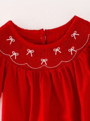 Girls red romper with bow smocking and embroidery, angle view showcasing stylish design and playful details.