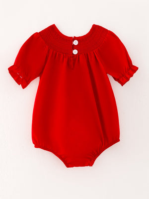 Girls red romper with bow smocking and embroidery, angle view showcasing its cute design and details.