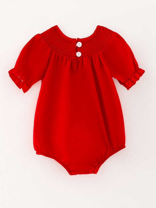 Girls red romper with bow smocking and embroidery, angle view showcasing its cute design and details.