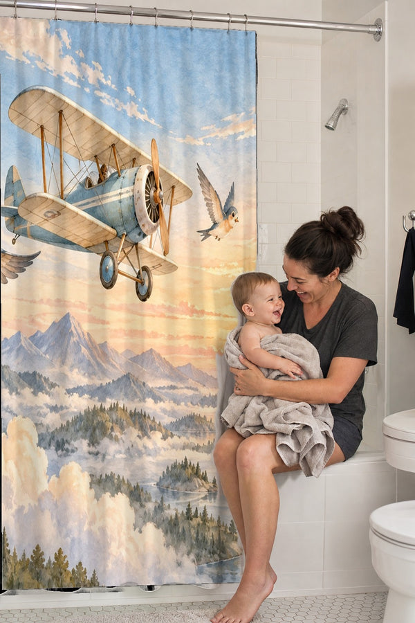 Mom holding her baby on the tub edge next to the Birds and Biplane shower curtain