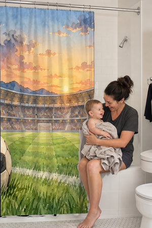 Mom holding her baby on the tub edge next to the Stadium Sunset Soccer shower curtain