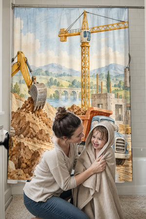 Mom drying her toddler in a hooded towel in front of the Construction Site shower curtain