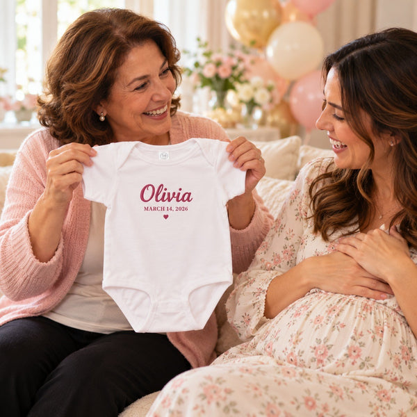 Grandma holding up the embroidered Olivia name and birth date bodysuit at a baby shower