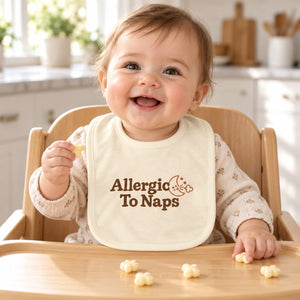 Allergic To Naps baby bib in cream, styled photo 1