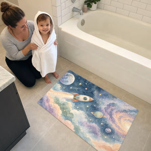 Mom and toddler in a hooded towel next to the Rocket Journey bath mat