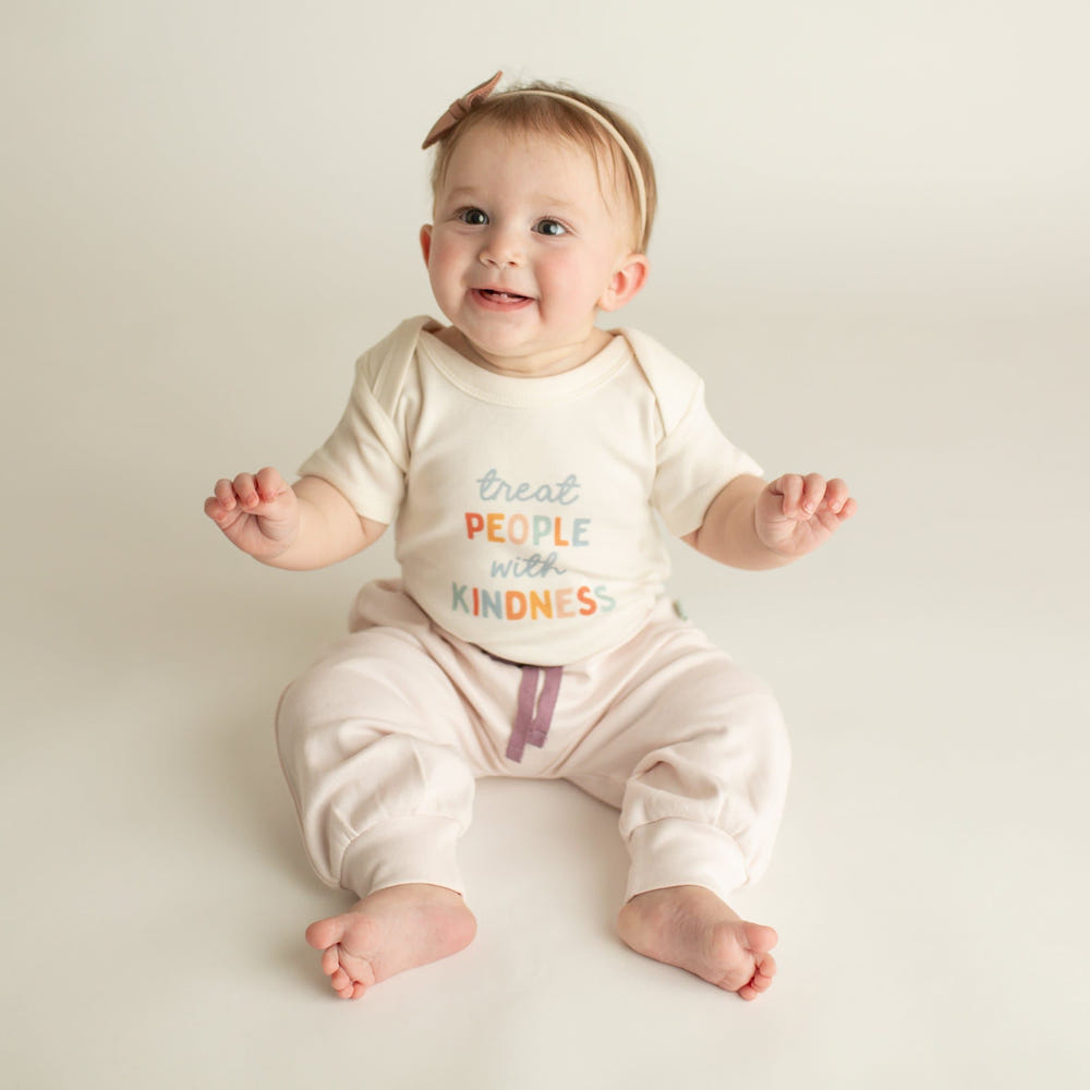 Graphic bodysuit for babies featuring "Treat People with Kindness" design, perfect for stylish and positive little ones.