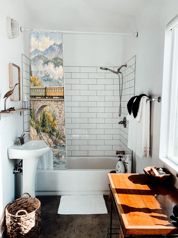 Mountain Bridge Train shower curtain hanging on the rod over a white bathtub