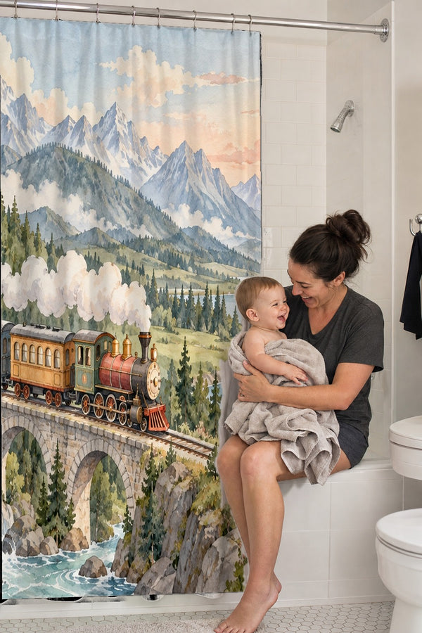 Mom holding her baby on the tub edge next to the Panoramic Train Journey shower curtain