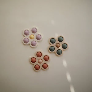 Colorful flower press toy for babies, showcasing vibrant petals and playful design at a 27-degree angle.