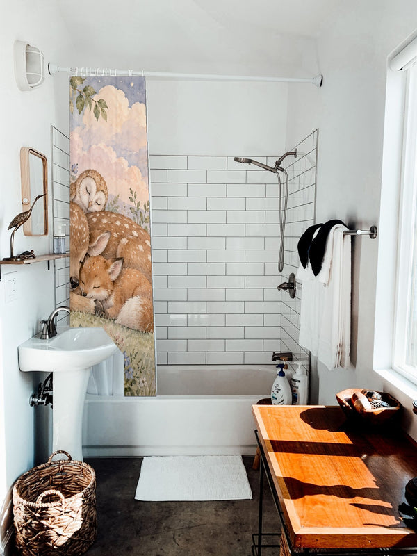 Dreamland Friends shower curtain hanging on the rod over a white bathtub