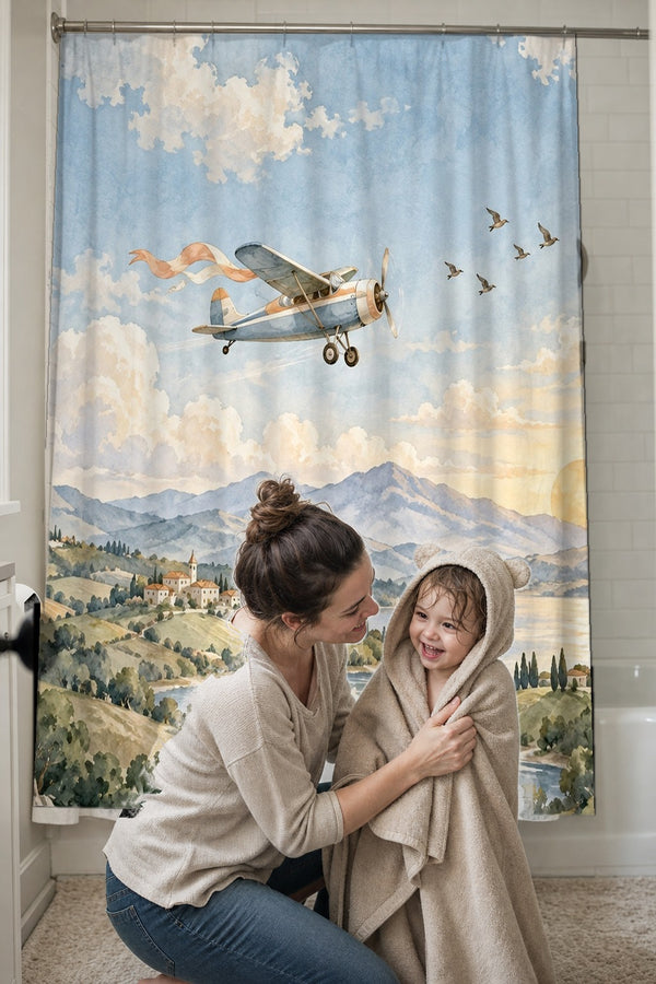 Mom drying her toddler in a hooded towel in front of the Balloon and Plane shower curtain