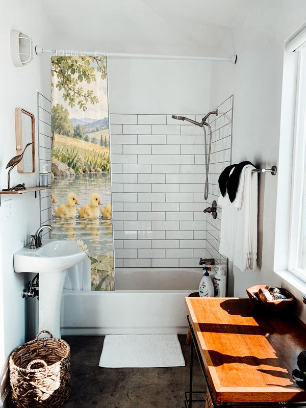 Ducklings Pond Farm shower curtain hanging on the rod over a white bathtub