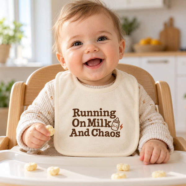 Running On Milk And Chaos baby bib in cream, styled photo 1