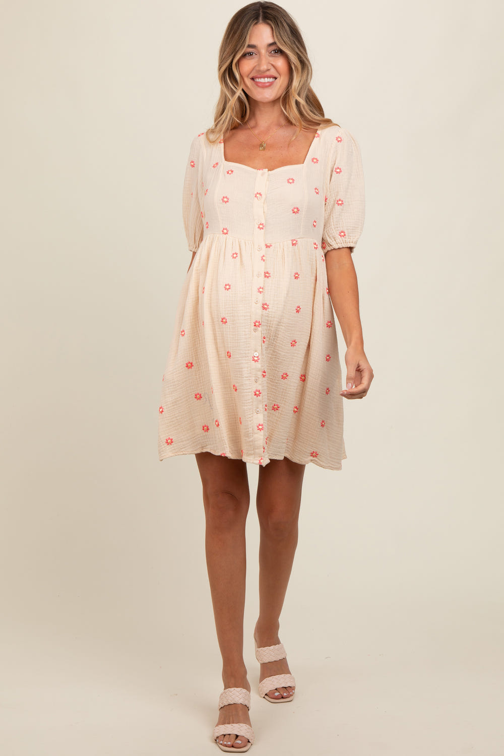 Beige floral embroidered maternity dress with button front and short sleeves, perfect for expecting mothers.