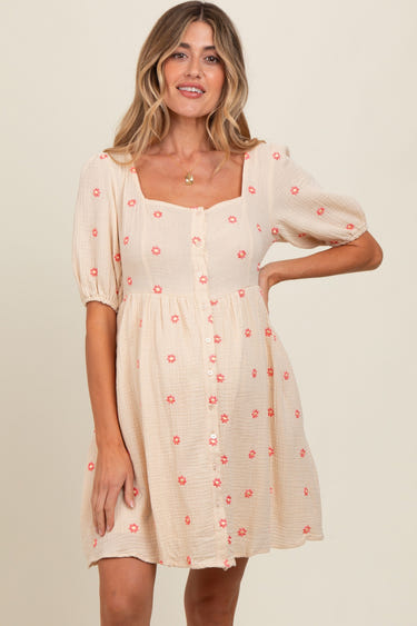 Beige floral embroidered maternity dress with button front and short sleeves, perfect for expecting mothers.