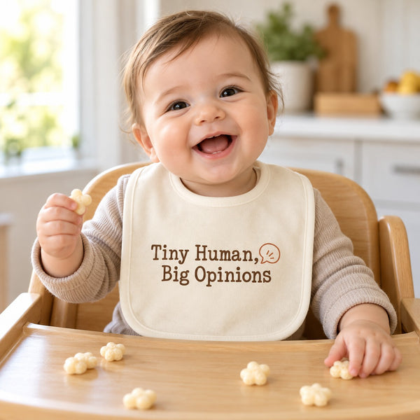 Tiny Human, Big Opinions baby bib in cream, styled photo 1