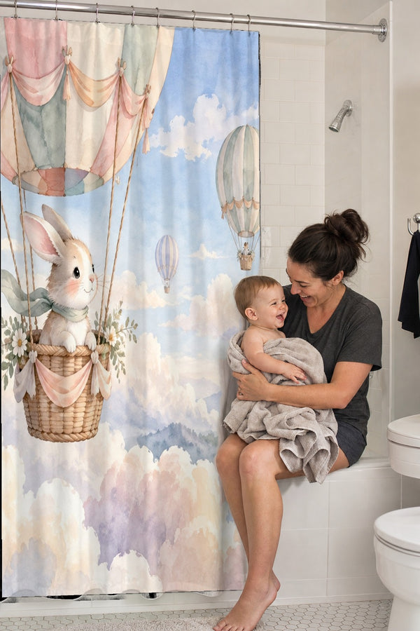 Mom holding her baby on the tub edge next to the Bunny Hot Air Balloon shower curtain