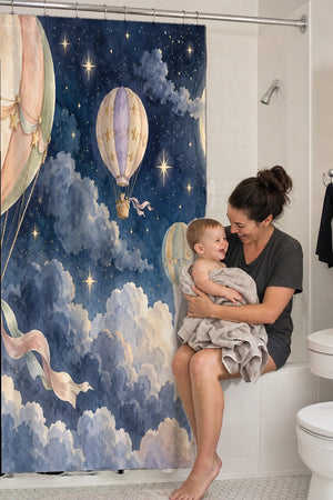 Mom holding her baby on the tub edge next to the Moonlit Flight Hot Air Balloon shower curtain