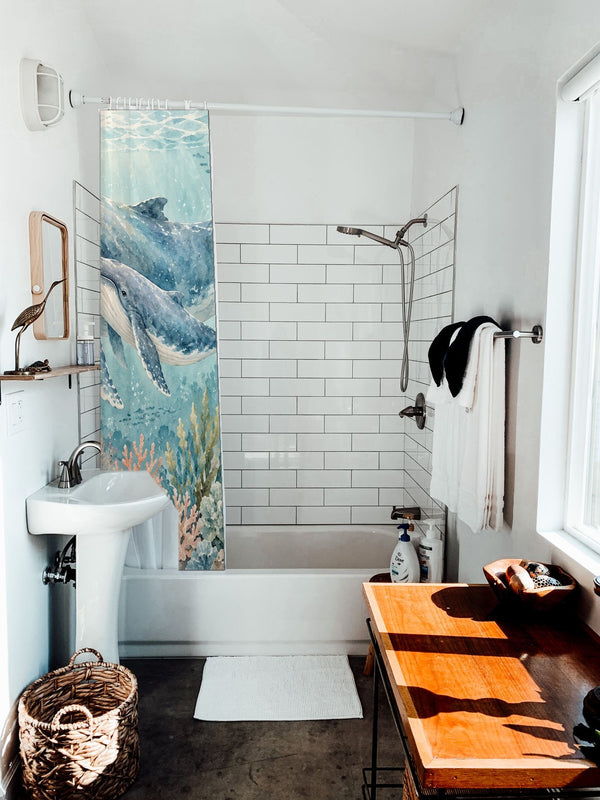 Whale Family Ocean shower curtain hanging on the rod over a white bathtub