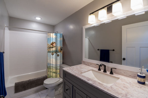 Vintage Airplane shower curtain pulled open in a gray kids bathroom