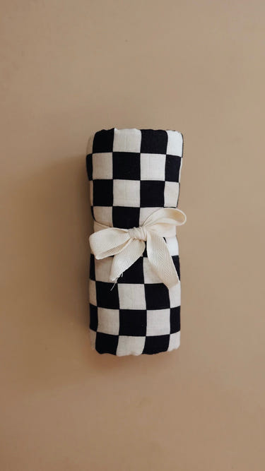 Black and white checkerboard muslin swaddle for babies, soft and breathable for comfort and style.