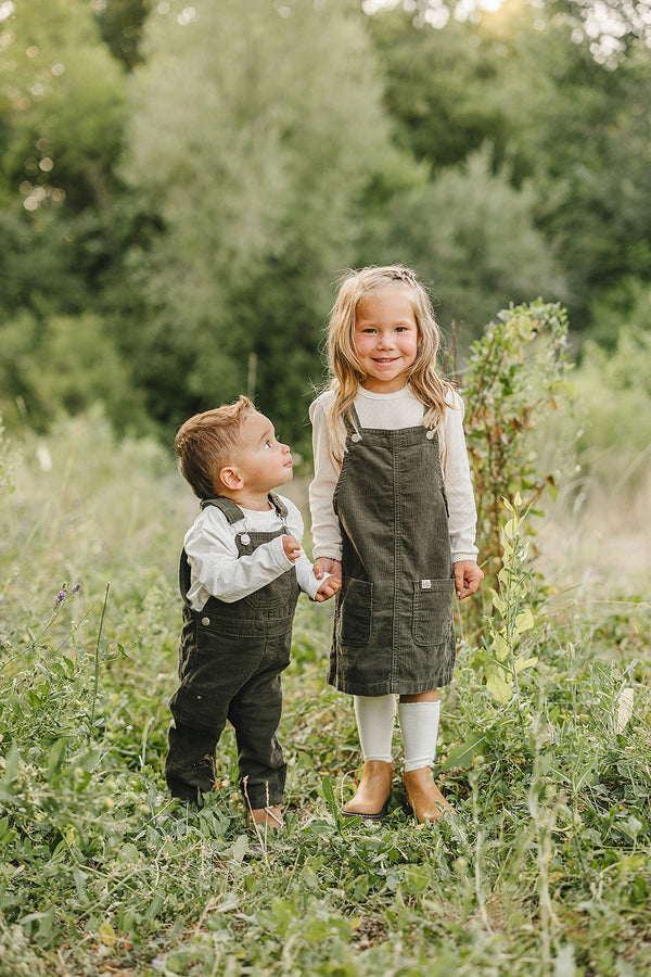 Green corduroy dress for babies, angle view showcasing soft fabric and stylish design. Perfect for any occasion.