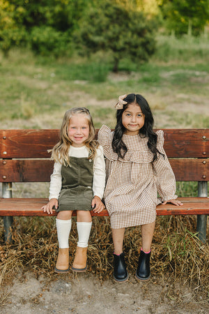 Green corduroy dress for babies, angled view showcasing soft texture and stylish design. Perfect for any occasion.