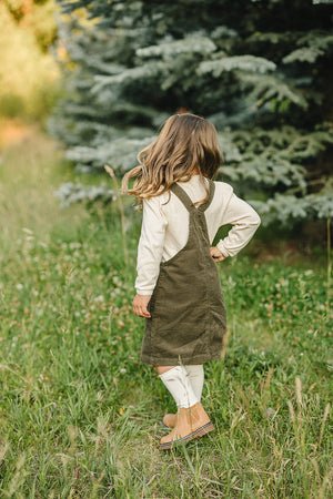 Green corduroy dress for babies, angle view showcasing soft fabric and stylish design. Perfect for any occasion.